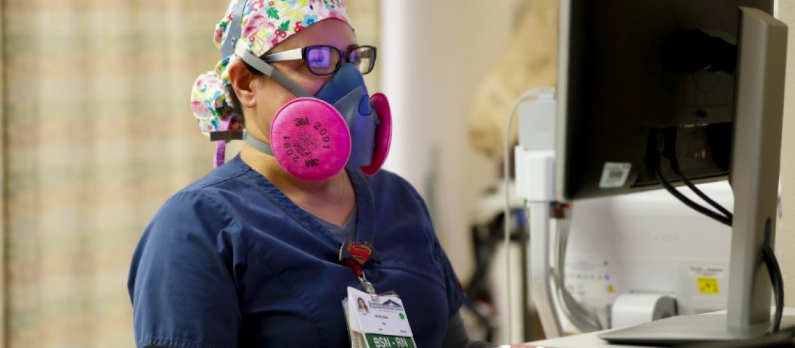 Working in the ER at El Centro Regional Medical Center, Evelina Gonzalez, RN wears a half face mask fitted with a P100 filter while updating a patient’s chart.(Nelvin C. Cepeda / The San Diego Union-Tribune)